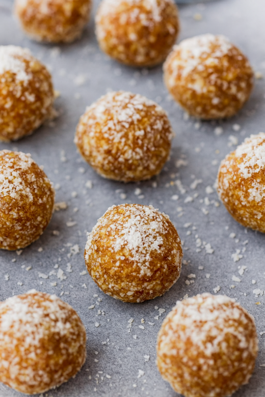 Lemon–cashew bliss balls coated in coconut flakes on parchment paper.
