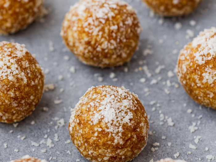 Lemon–cashew bliss balls coated in coconut flakes on parchment paper.